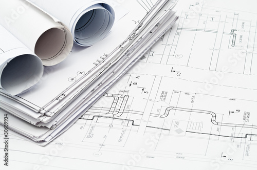Heap of design and project drawings on desk.