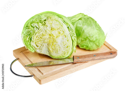 Fresh green iceberg lettuce with knife on wooden chopping board