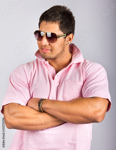 Young fashion man model with athletic body posing in sun glasses photo