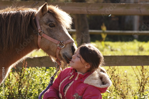 enfant avec un  poney lui faisant un bisou photo