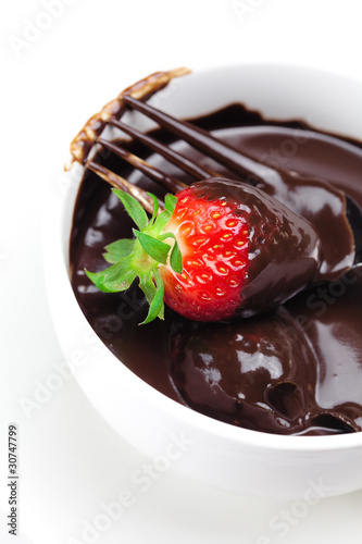 melted chocolate in a cup  fork and strawberries isolated on whi