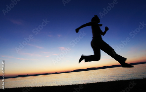 Young woman jumping on a beach at sunset