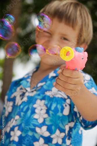 young boy playing with bubbles on natural background