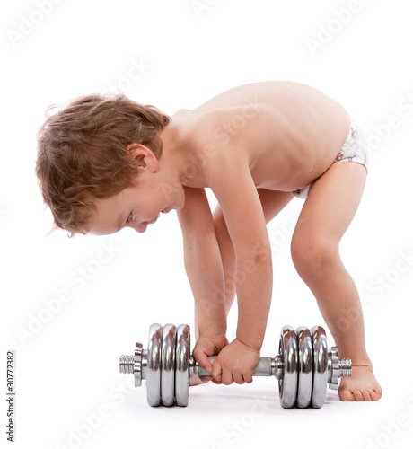 Little boy trying to lift  heavy dumbbell photo