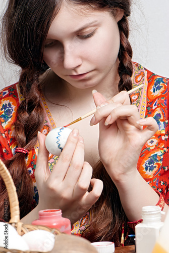 portrait of a young girl who is painting an egg for easter photo