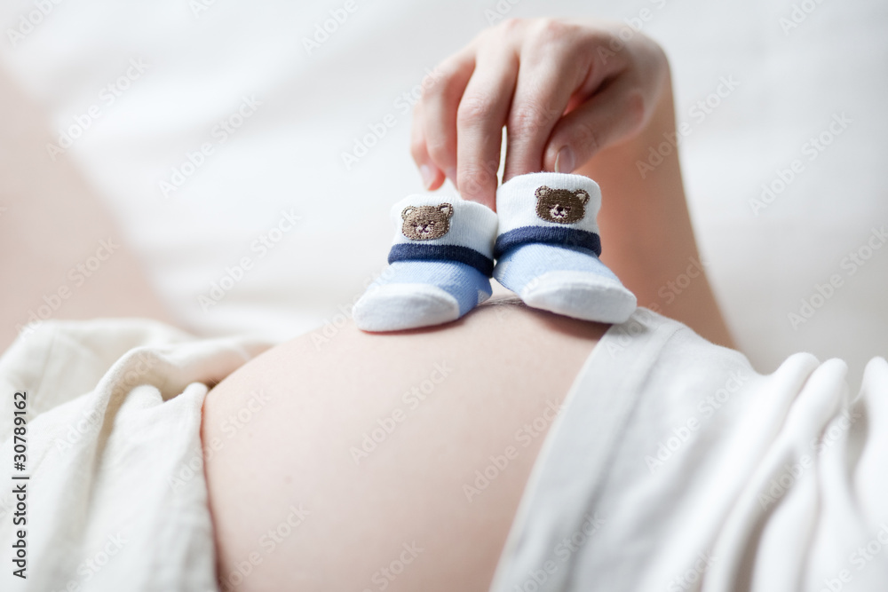 schwangere Frau mit Babyschuhen auf dem Bauch