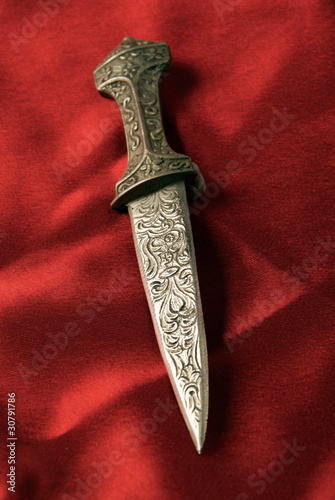Antique dagger on red stain background