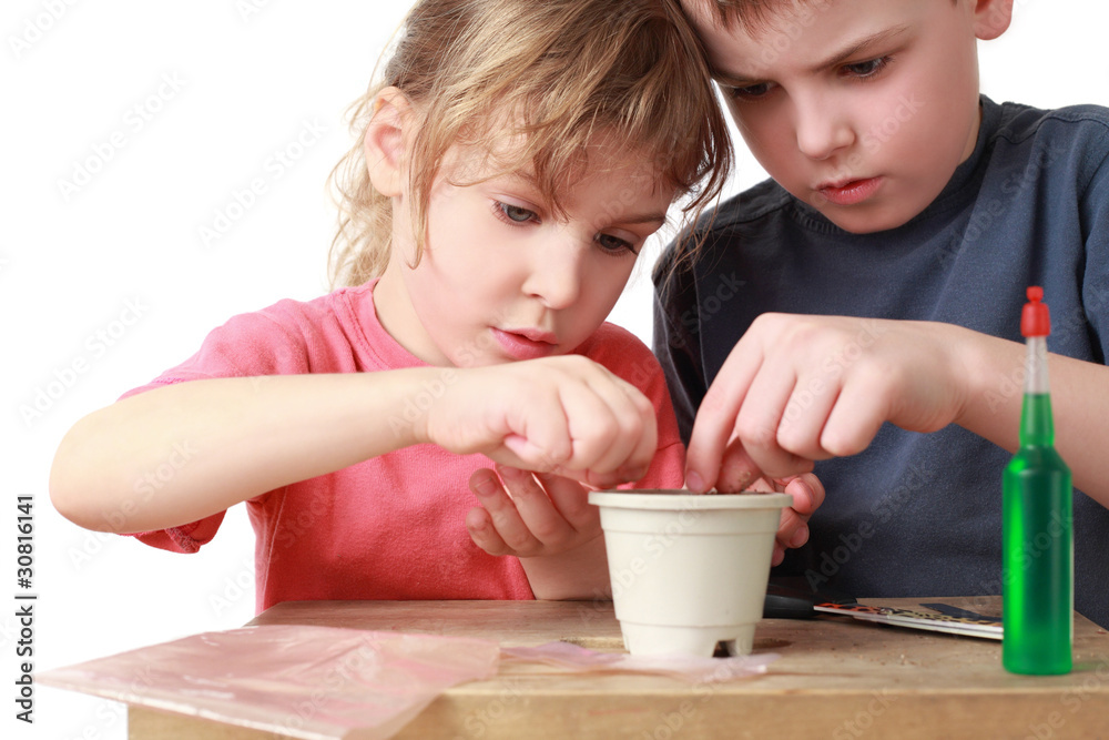 Girl and boy seat grains in pot Girl and boy seat grains in pot
