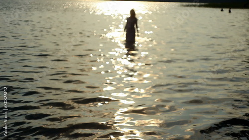 girl walking in from the sea at sunset