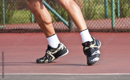 Tennis player legs and feet on court playing