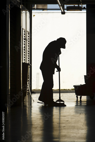 Silhouette of man moping floor photo