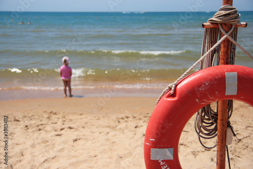 Life buoy on seacoast and the child at water on a background