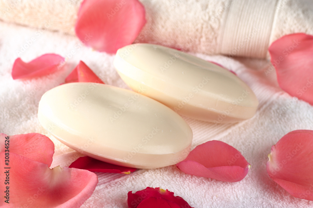 Two soap bars on towels with pink and red rose petals Two soap bars on towels with pink and red rose petals