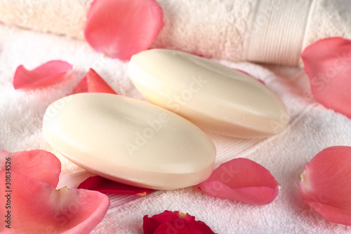 Two soap bars on towels with pink and red rose petals