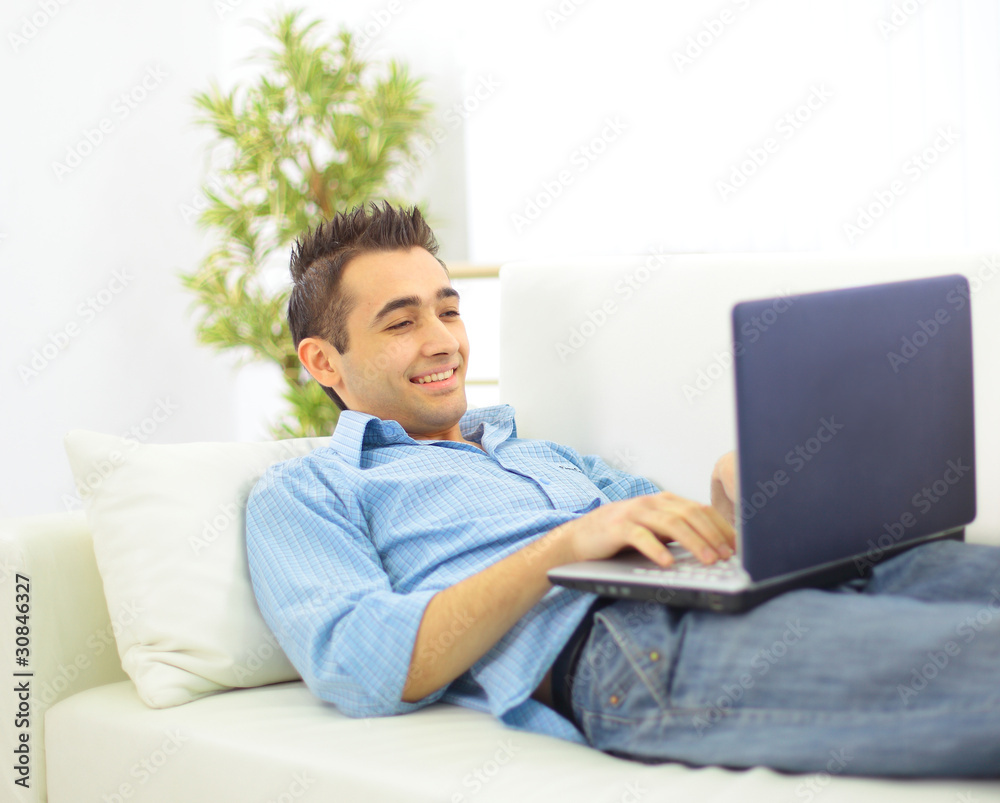 A smiling man with a laptop looks back A smiling man with a laptop looks back
