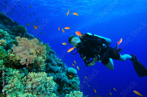 Young Woman Scuba Diving among tropical fish