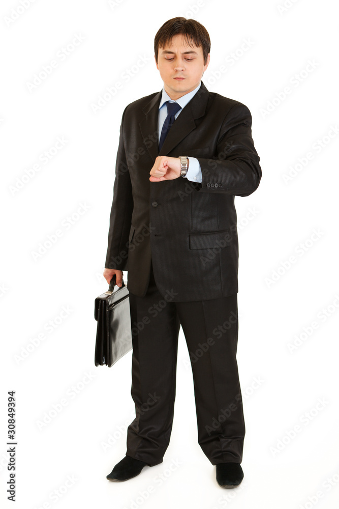 Serious businessman with suitcase looking at watch Serious businessman with suitcase looking at watch