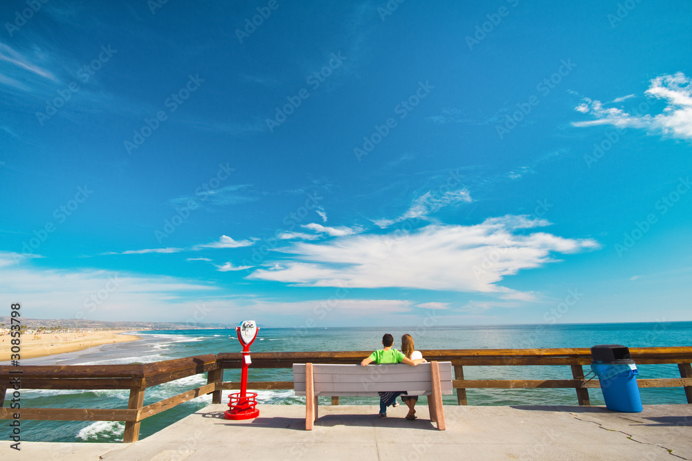 Sweet Young Couple Sitting on Bench at the Pier