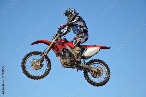 motocross rider flying high in the air against the blue sky
