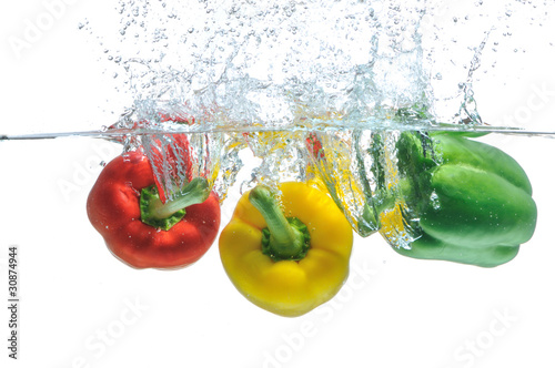 Three peppers falling in water