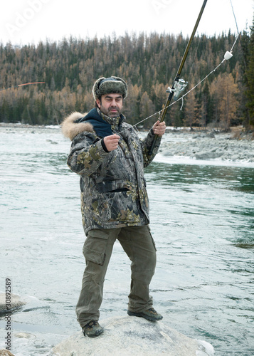 A fisherman on the river in winter