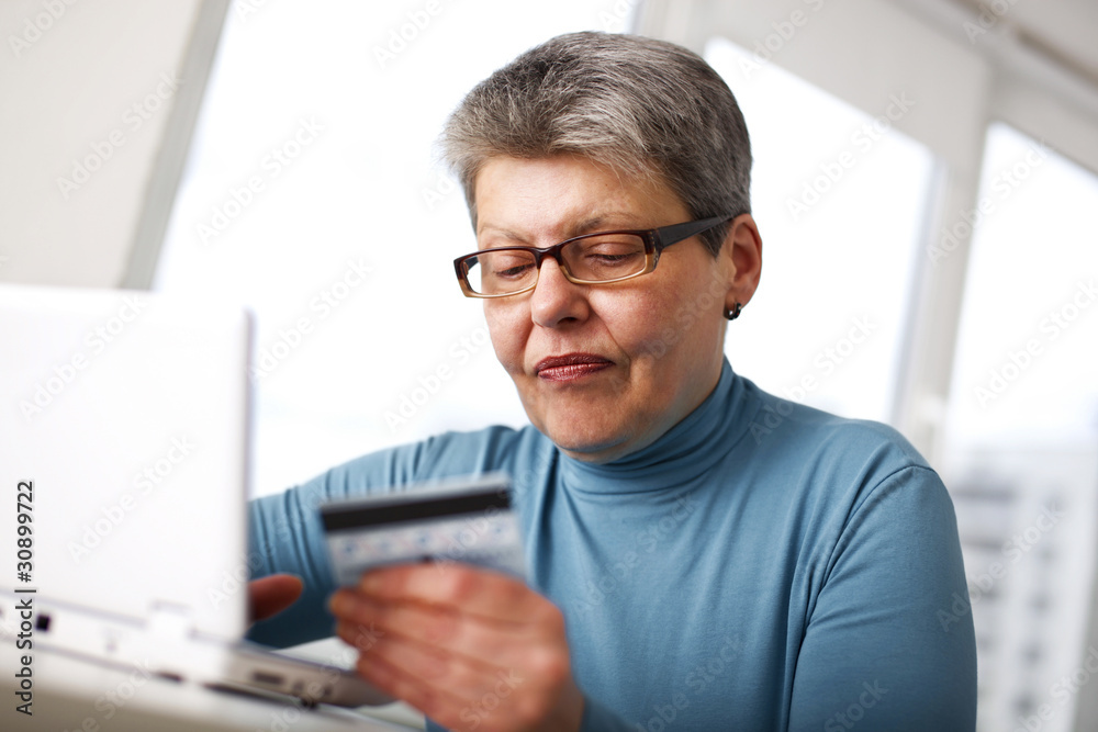 senior woman using credit card and laptop