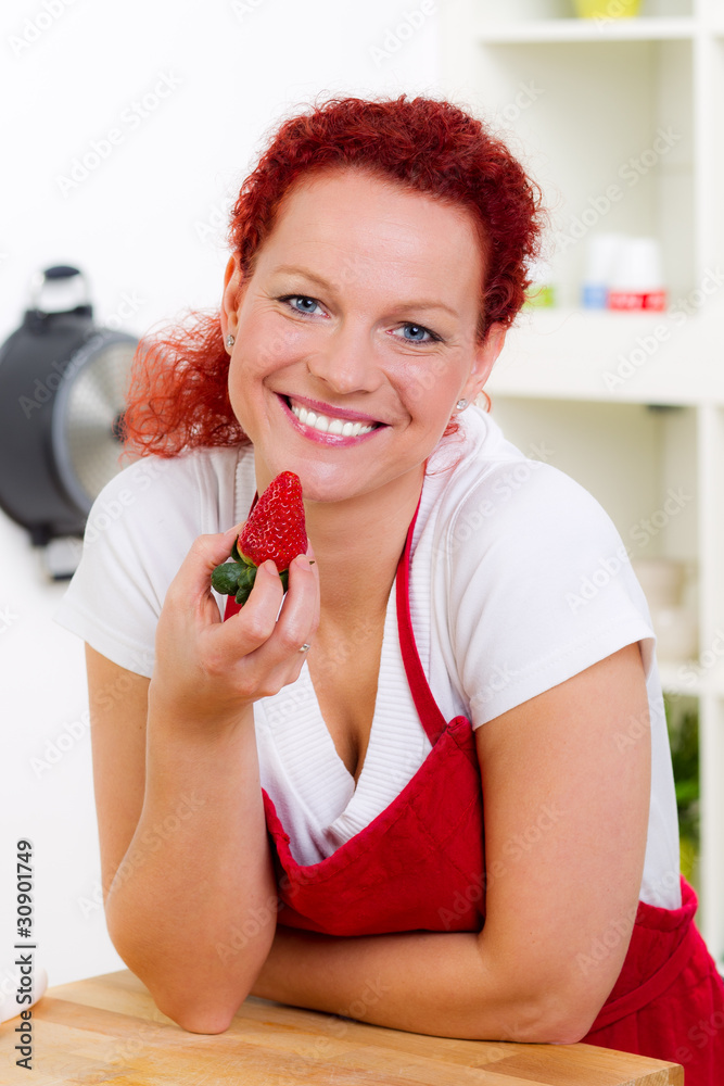 glückliche frau hält eine erdbeere in der hand