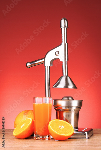 Juicer and oranges on red background