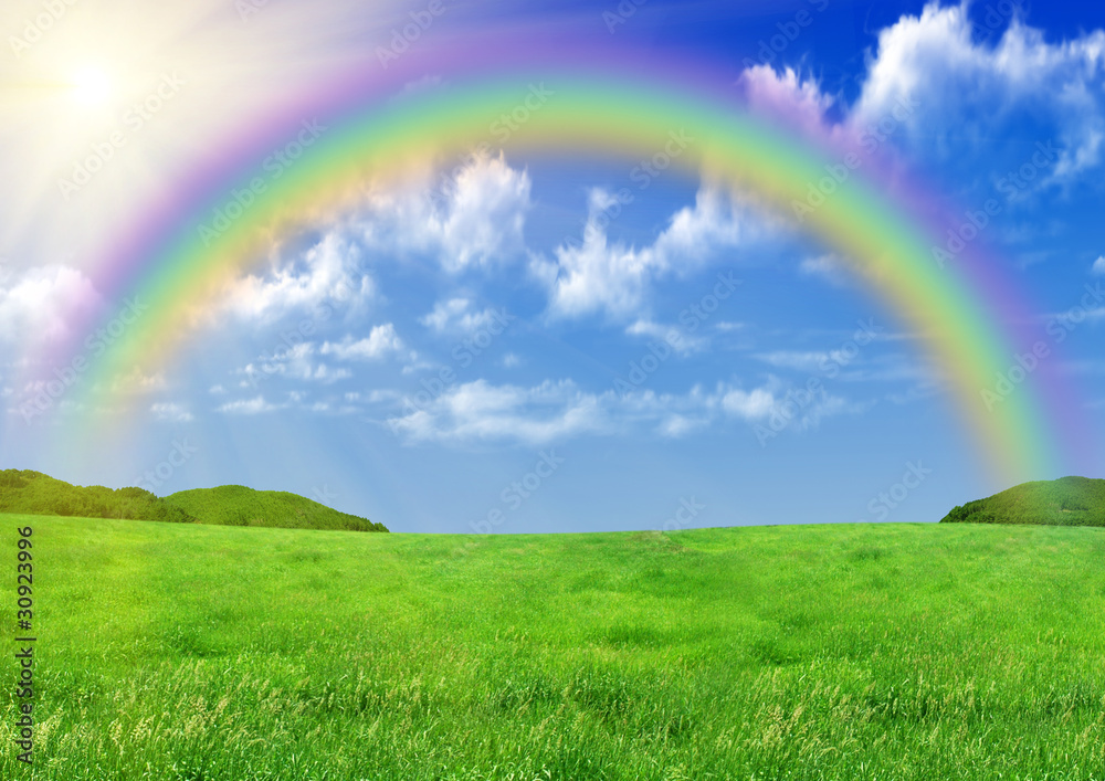 Rainbow in the blue sky over a glade Rainbow in the blue sky over a glade