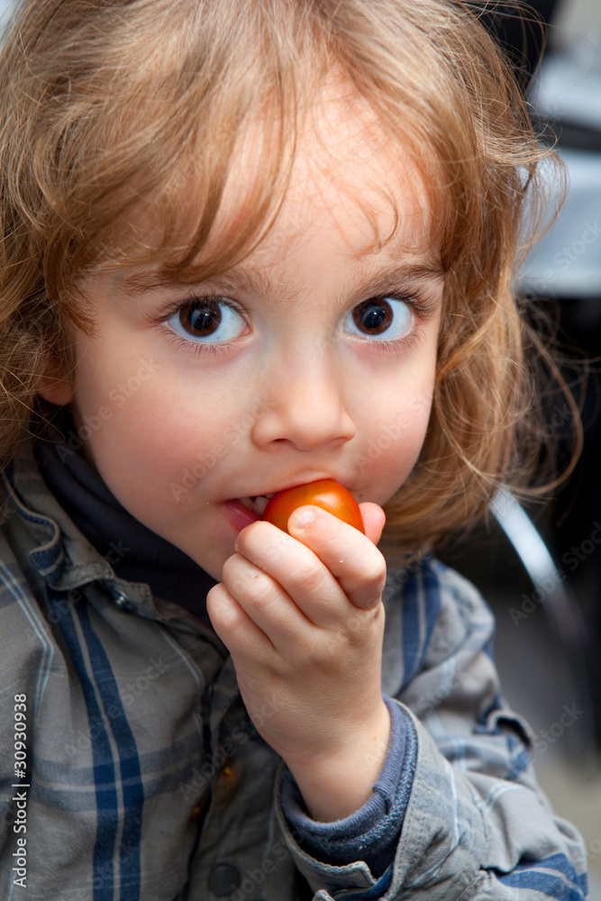 Enfant qui mange une tomate cerise Enfant qui mange une tomate cerise