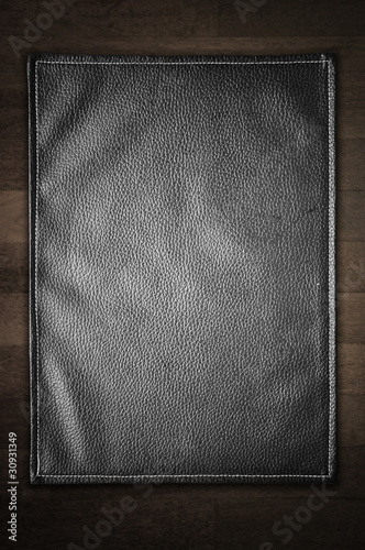 A black leather texture isolated on the wooden background.