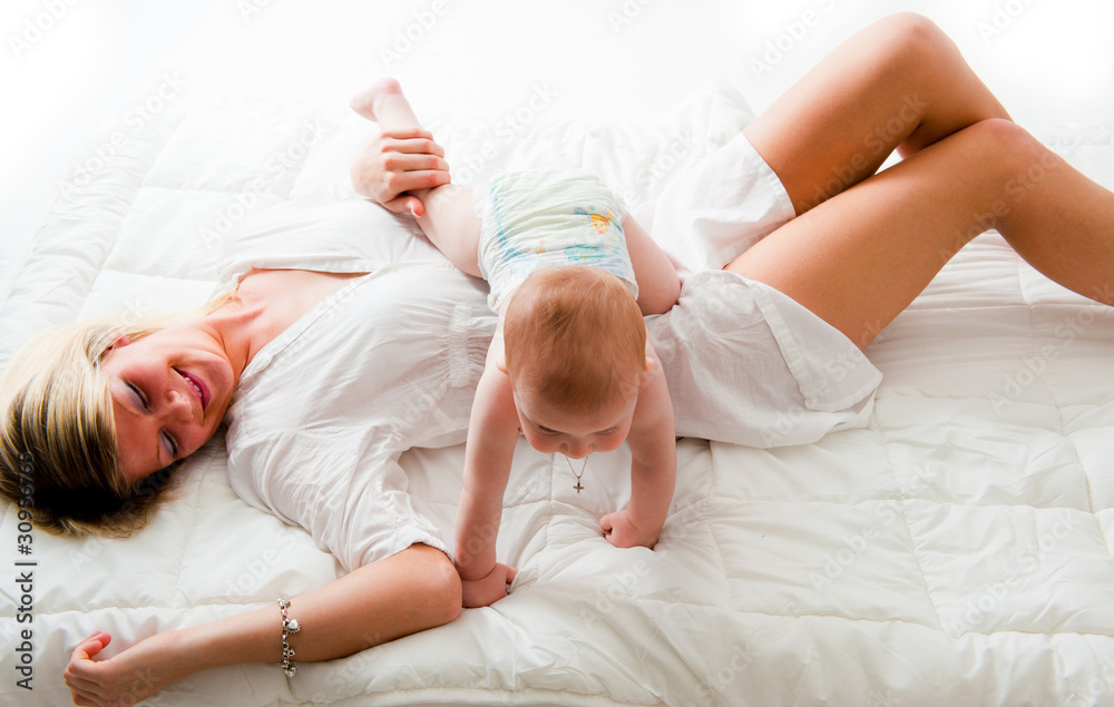Junge Mutter spielt mit ihrem Sohn auf dem Bett Junge Mutter spielt mit ihrem Sohn auf dem Bett
