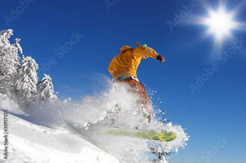 Snowboarder  jumping against blue sky photo