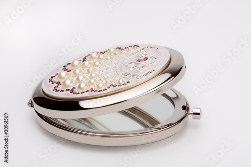 Round pocket mirror with pearls on white background