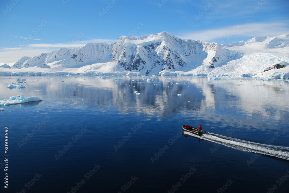 Naklejka premium boat cruises through antarctic landscape