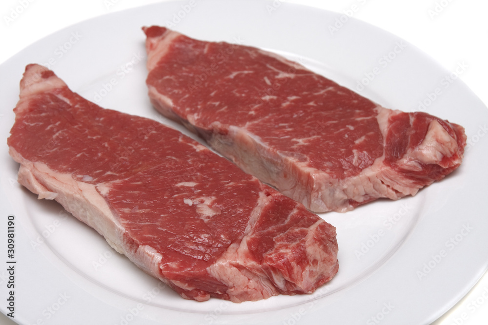 Two Strip Steaks on a White Plate Two Strip Steaks on a White Plate