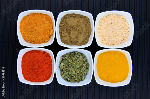 Different variety of spices on black mat