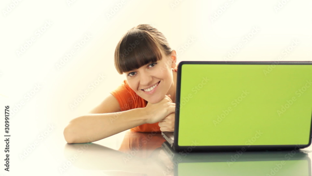 Happy smiling woman smiling behind laptop on glass table Happy smiling woman smiling behind laptop on glass table