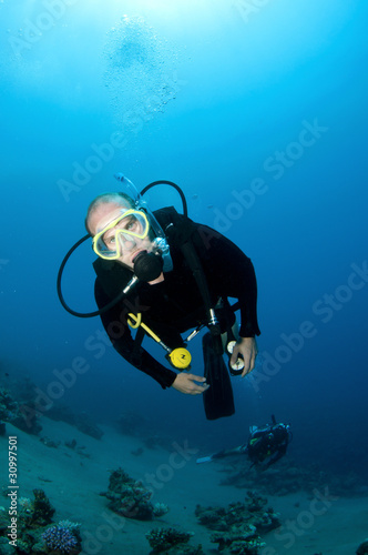 scuba diver swims in clear blue water