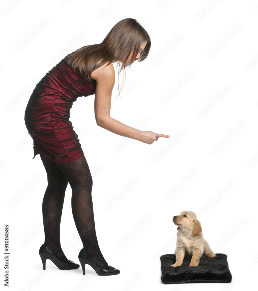 Εκτύπωση καμβά Young woman pointing her finger at Golden Retriever puppy