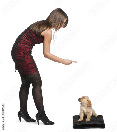 Foto Young woman pointing her finger at Golden Retriever puppy