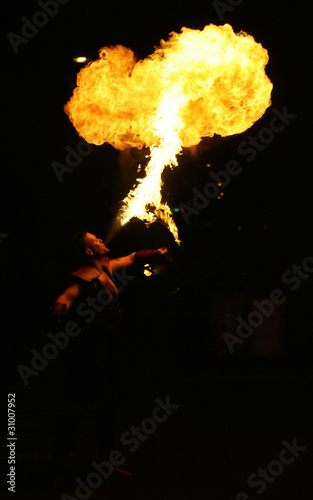 Fire breathing street performance artist at night.