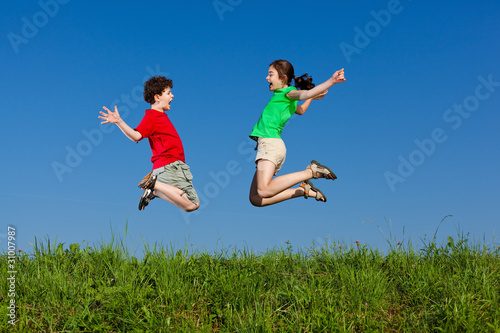 Girl and boy jumping  running against blue sky