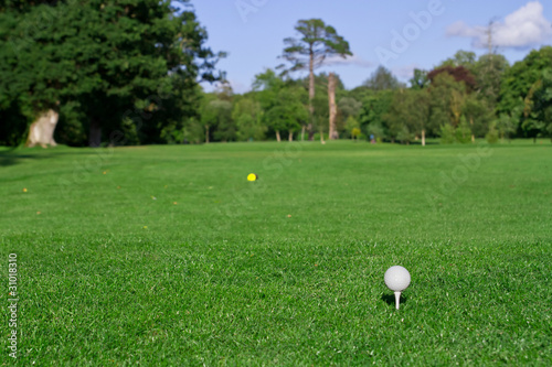 Golf ball on tee with blurry golf field background