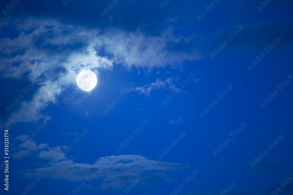 full moon over blue sky at a summer night with some clouds