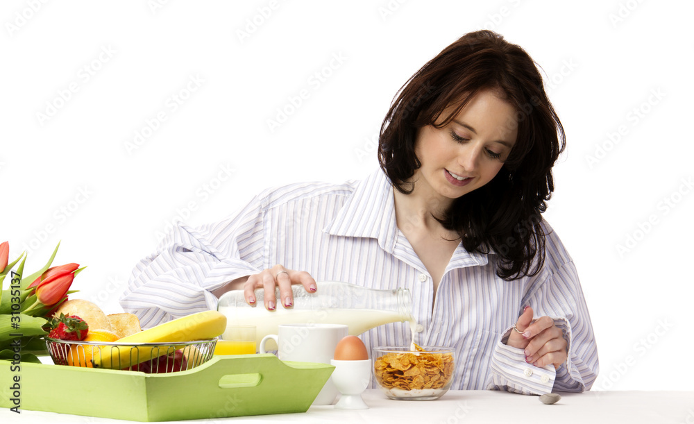 junge hübsche frau beim frühstück schüttet milch in corn flakes junge hübsche frau beim frühstück schüttet milch in corn flakes