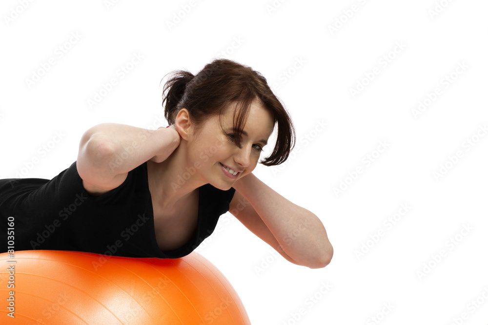 Fototapeta premium junge hübsche frau trainiert mit einem orangenen gymnastikball