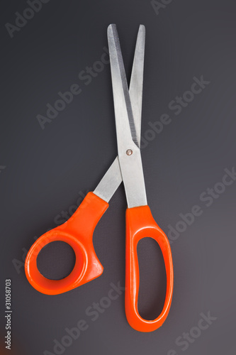 Orange scissors on the black background