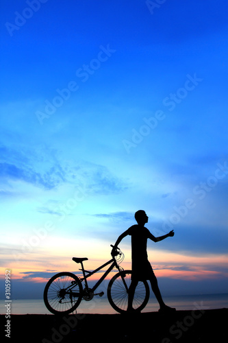 Silhouette of man riding bicycle with beautiful lake near by at