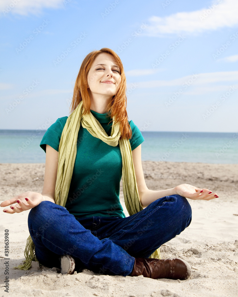 Young beautiful red-haired girl at the beach in spring time.